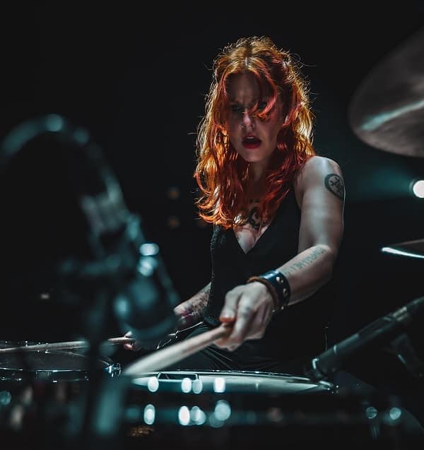 Woman playing drums live and hitting the snare drum
