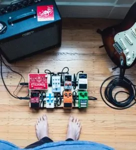 Guitar pedals in a chain with amp and electric guitar on a stand
