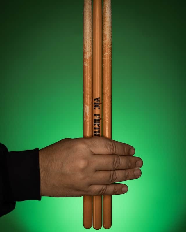 hand holding three drumsticks