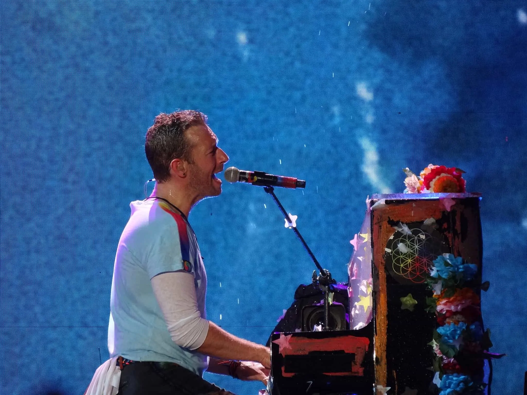 Chris martin playing piano and singing on stage