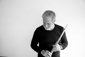 man in black holding a flute