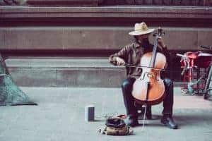 man in hat busking with cello