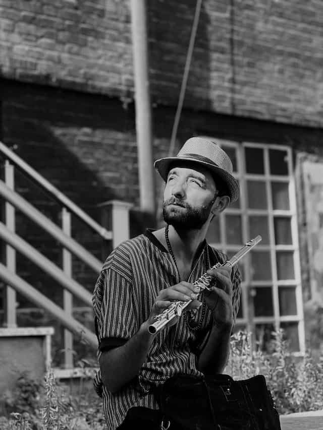 man outside holding flute black and white