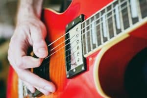 Guitarist using the O method of holding a pick on a Les Paul electric guitar