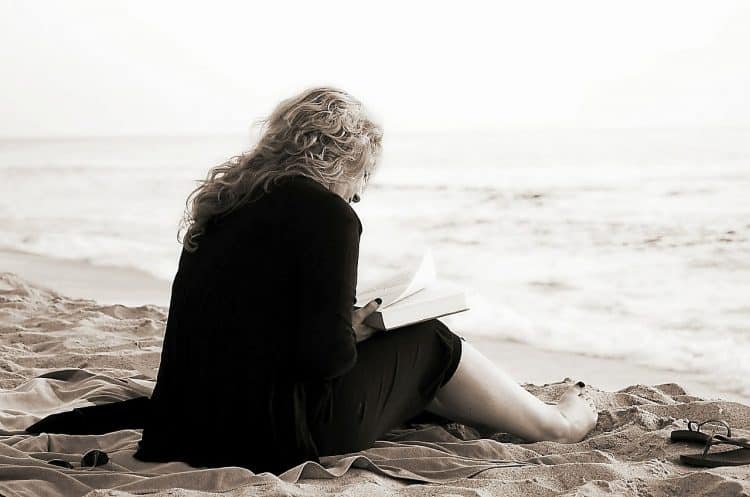 person reading a book on the beach taking a lot of time