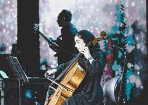 Cellist playing with a bow on stage.