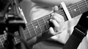 Guitarist using a capo on the fretboard