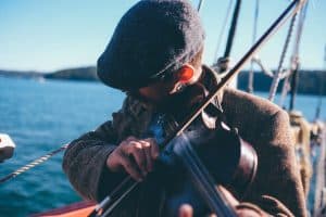 Man practising violin near the ocean